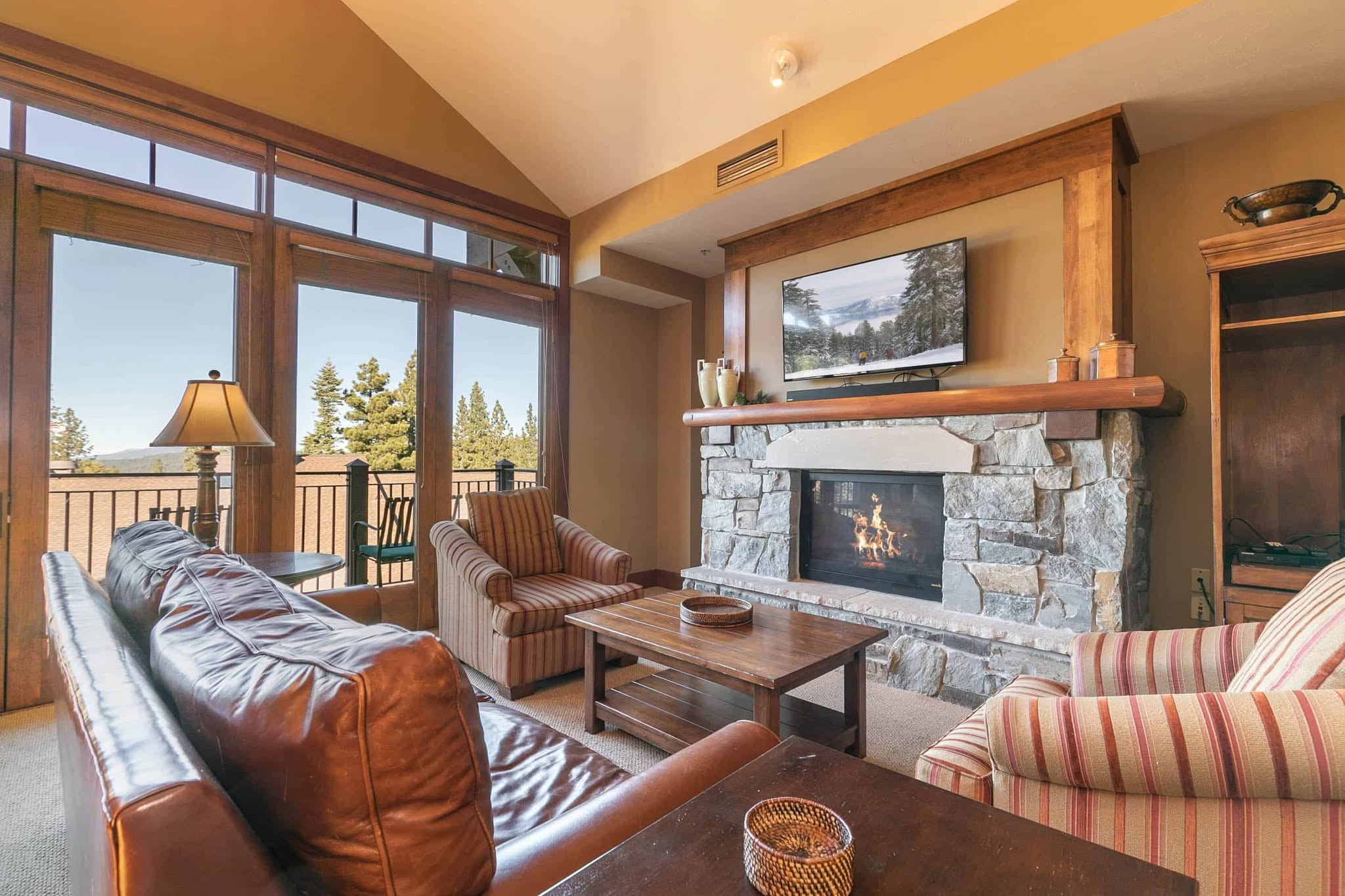 brown leather couch and comfy chairs in a living room in front of a fireplace
